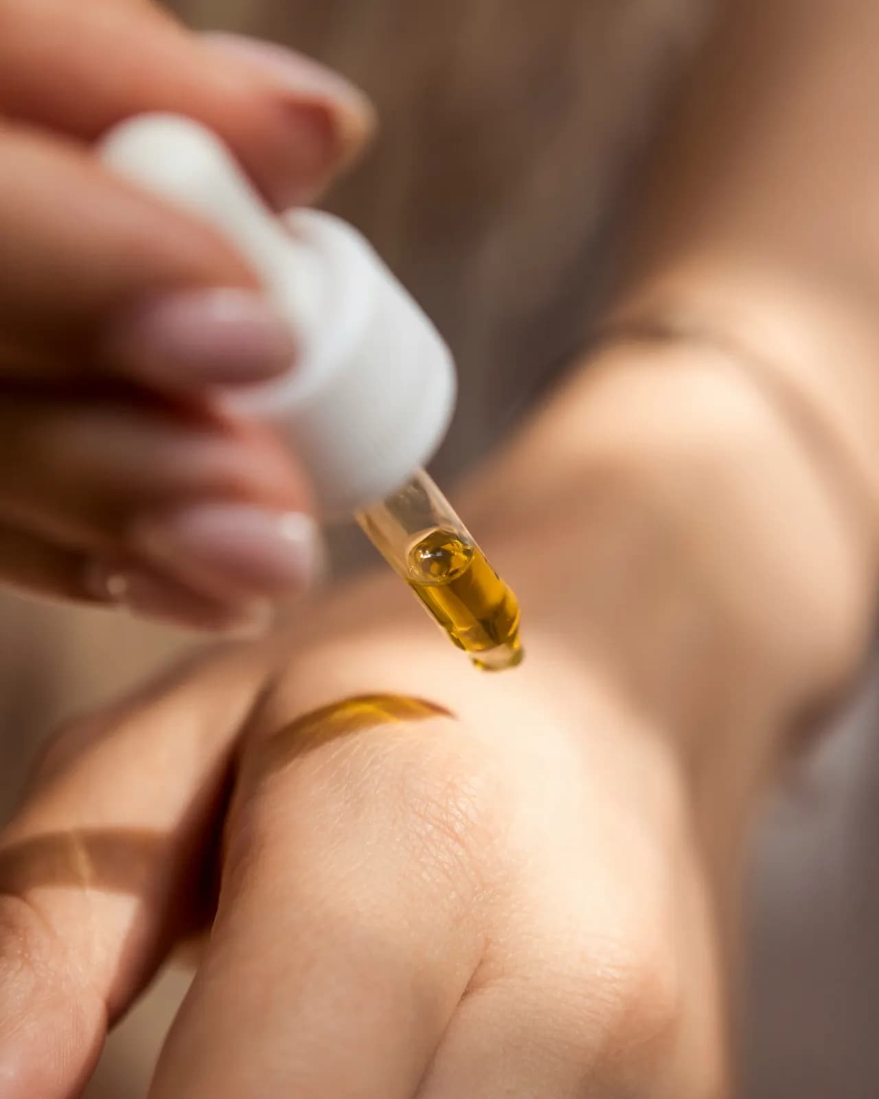 Une pipette d'huile au-dessus du dos de la main