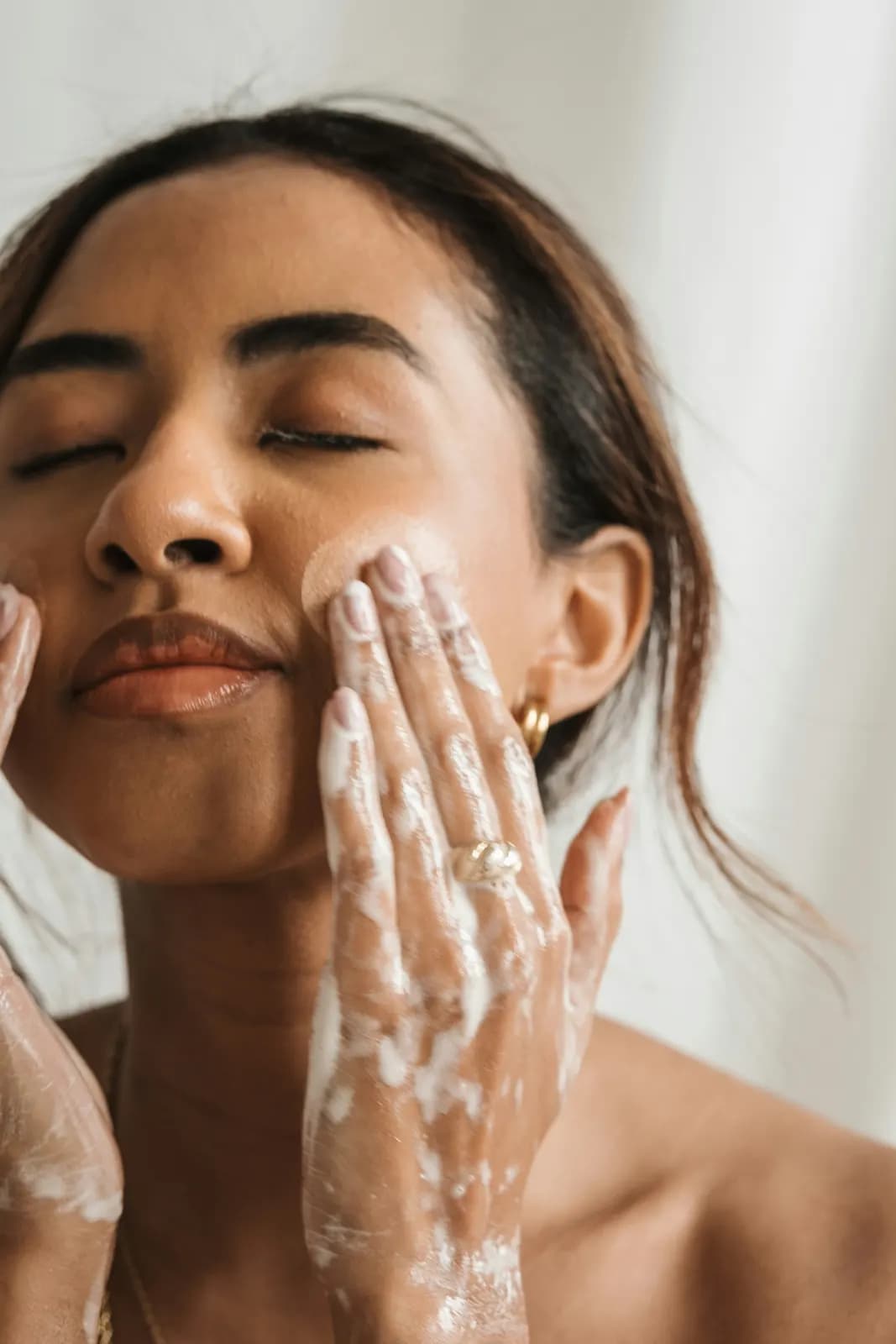 Une femme se nettoie le visage avec une mousse